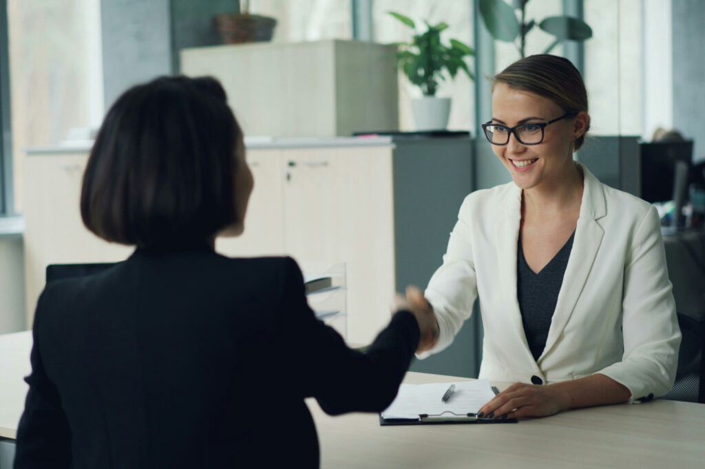 Woman shaking the hand of her ideal client after closing a deal.