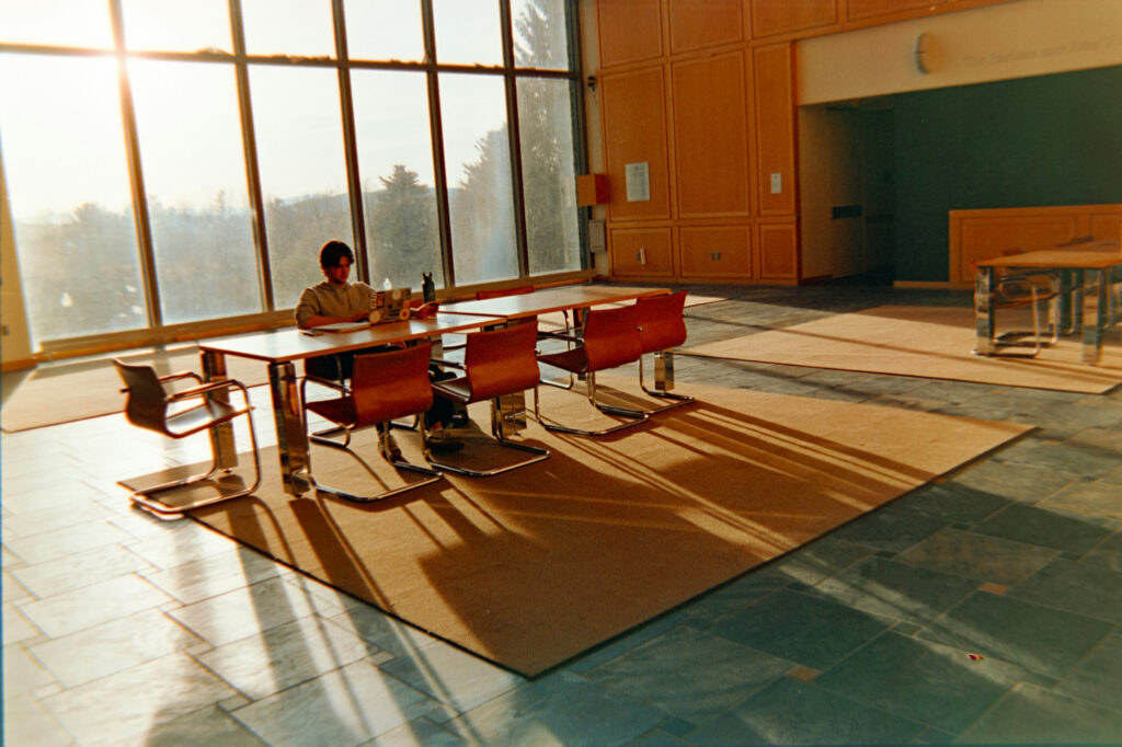 Man sitting alone in a large empty conference room instead of confronting his imposter syndrome.