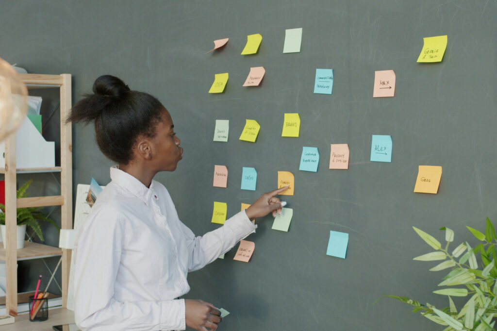 Woman examining one of the many sticky notes on a wall working on her marketing segmentation.