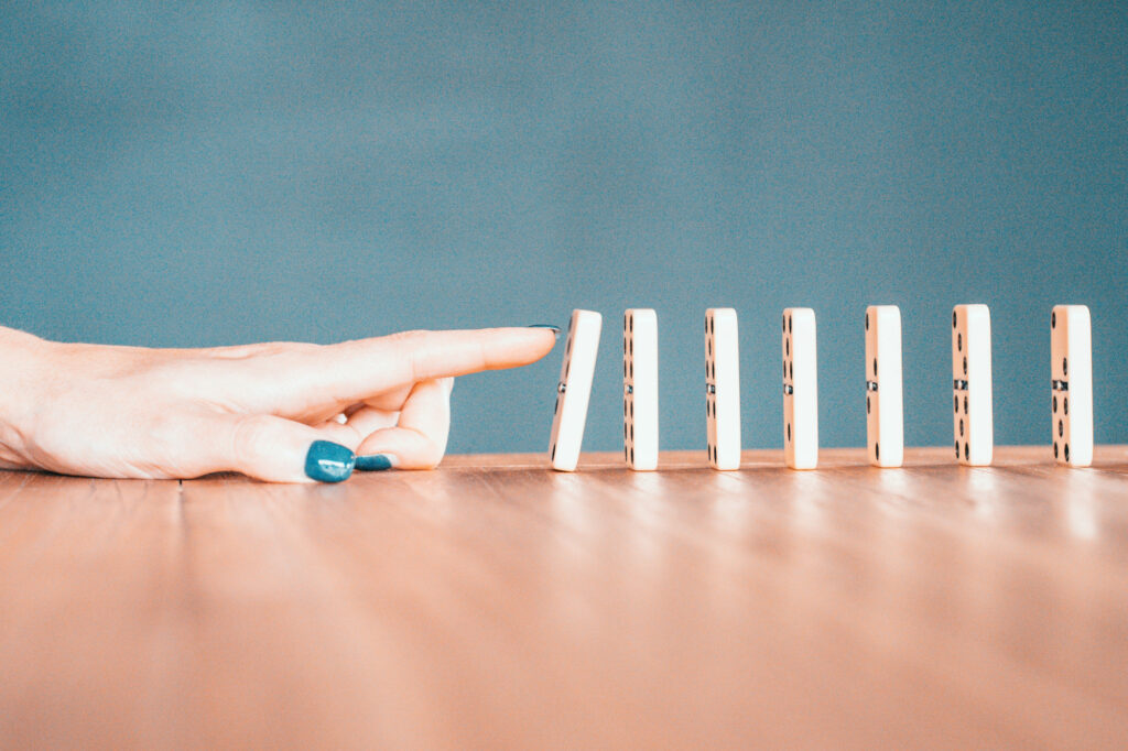 Woman knocking down the first in a series of dominoes as a representation of how to unlock business growth.