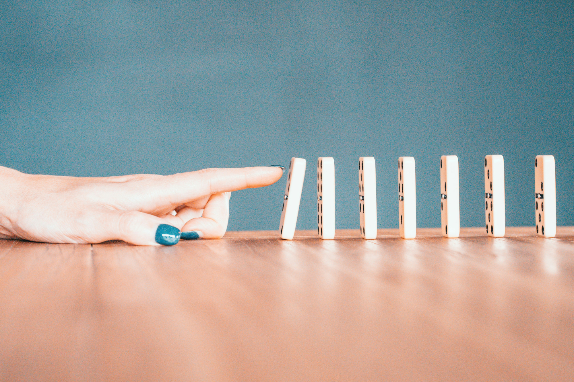 Woman knocking down the first in a series of dominoes as a representation of how to unlock business growth.