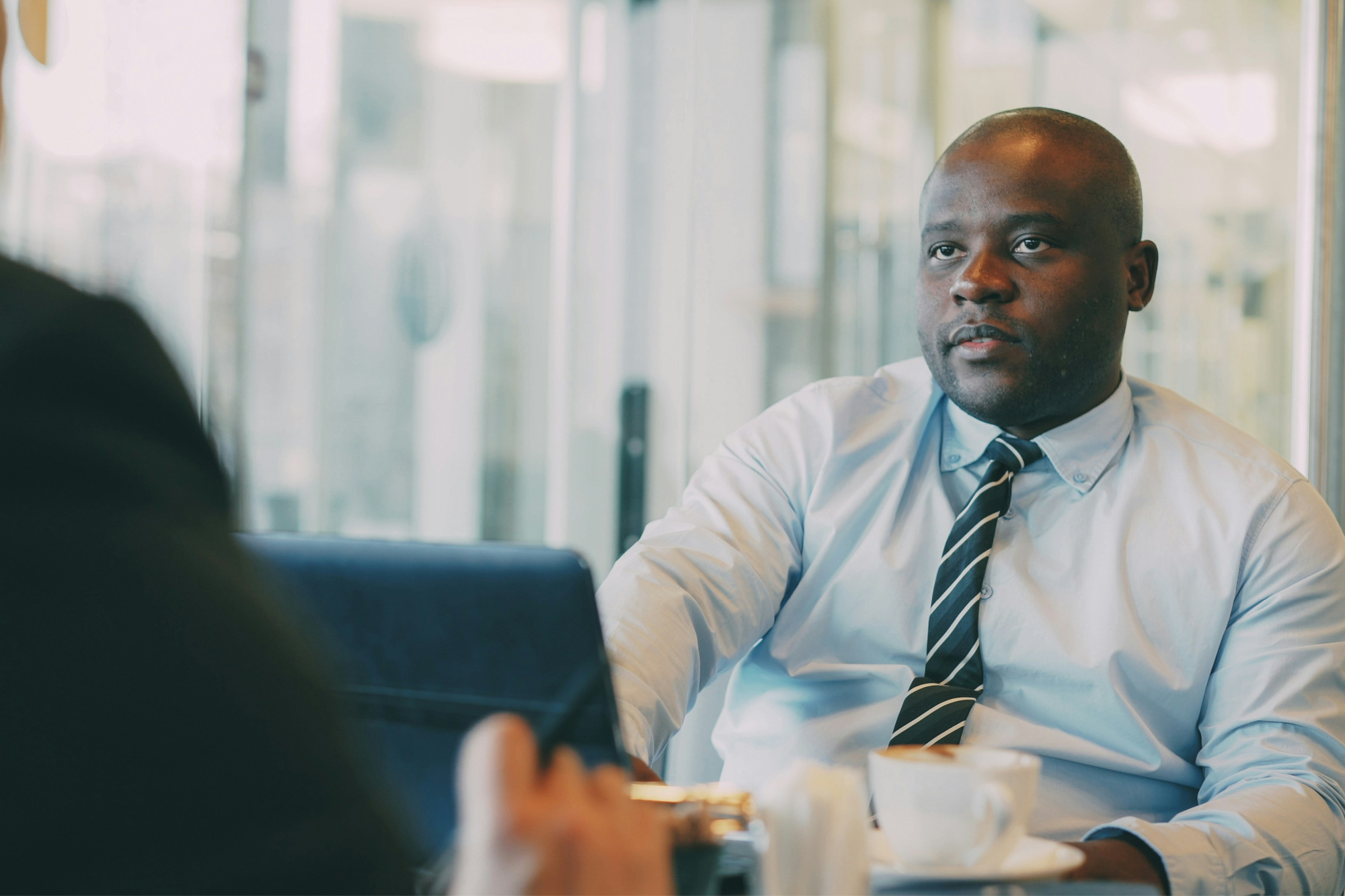Two professionals in a business conversation over coffee.