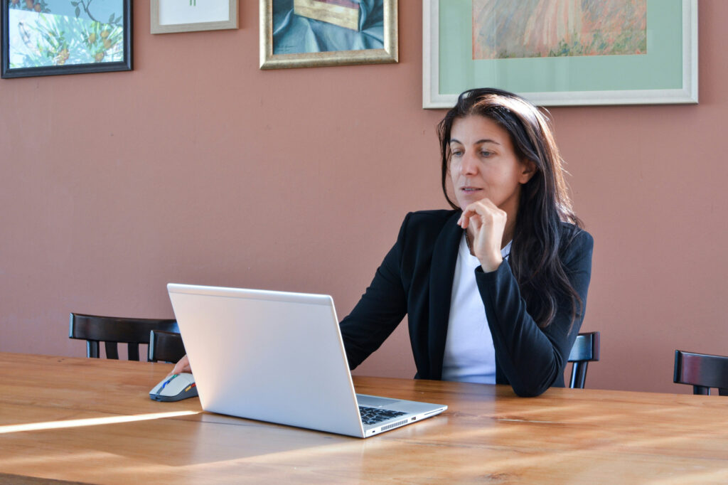 Business owner sitting at desk with laptop, thinking through a head trash problem that's keeping her business stuck.