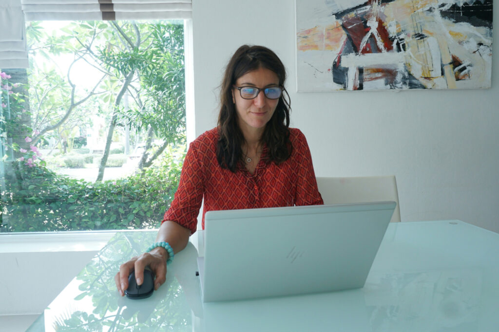Business owner working confidently at laptop with natural light, moving forward after clearing her head trash that was holding her business back