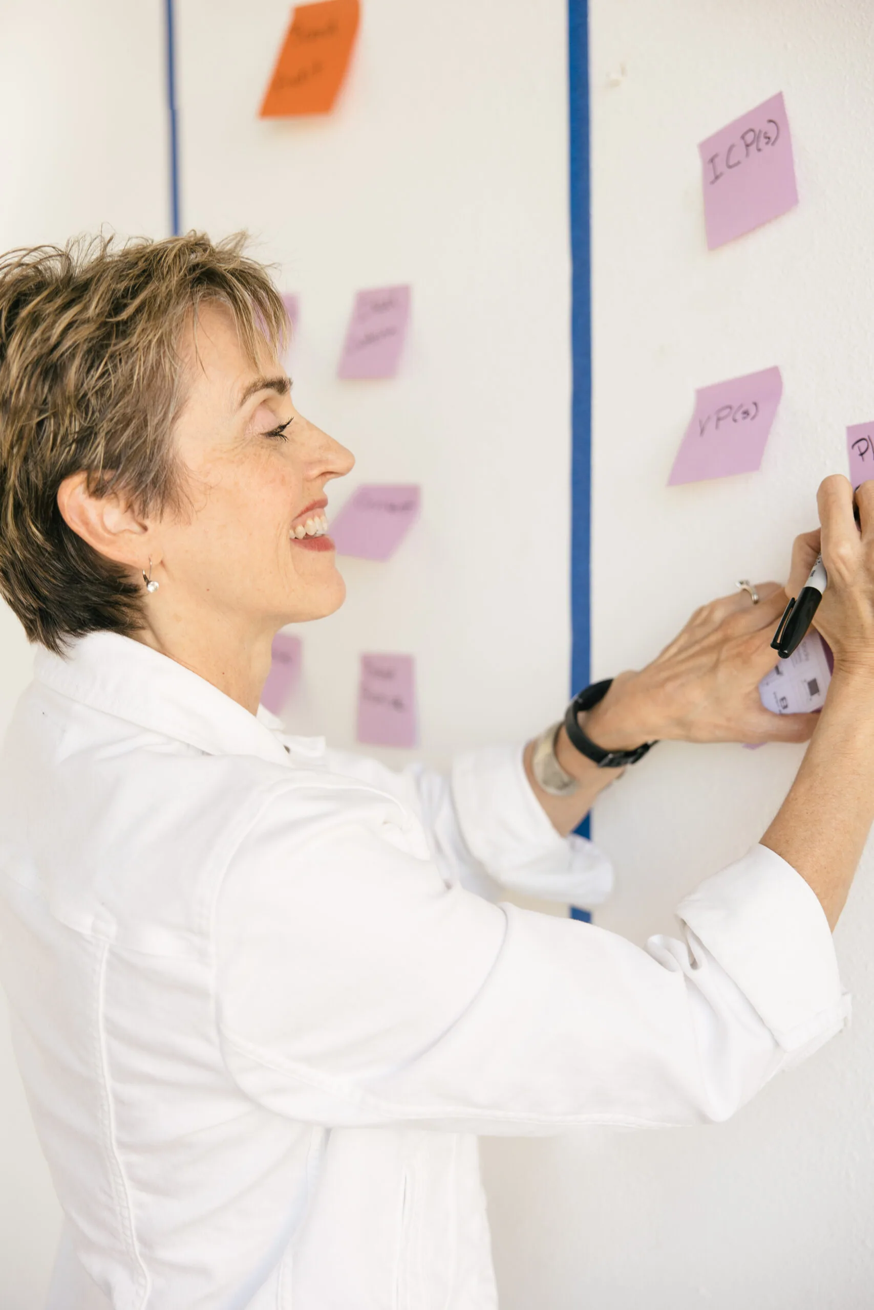 Karen Finn, PhD, smiling while mapping out a business growth plan on sticky notes
