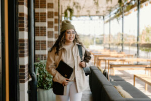 Business owner with a powerful entrepreneur mindset walking confidently through an outdoor business district carrying a portfolio bag.