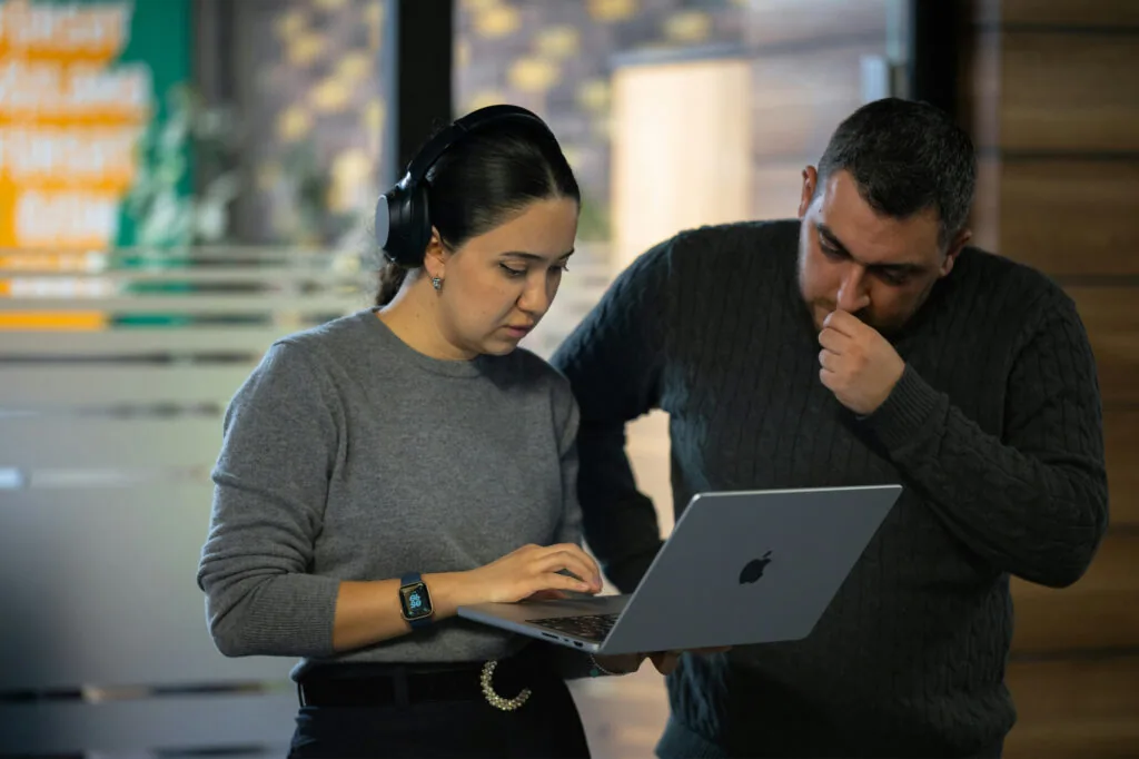 Small business owner evaluating the effectiveness of delegation with a colleague reviewing work on a laptop.
