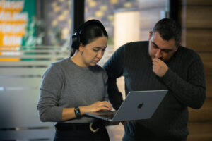 Small business owner evaluating the effectiveness of delegation with a colleague reviewing work on a laptop.