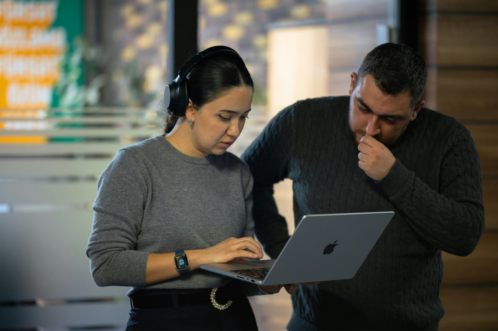 Small business owner evaluating the effectiveness of delegation with a colleague reviewing work on a laptop.
