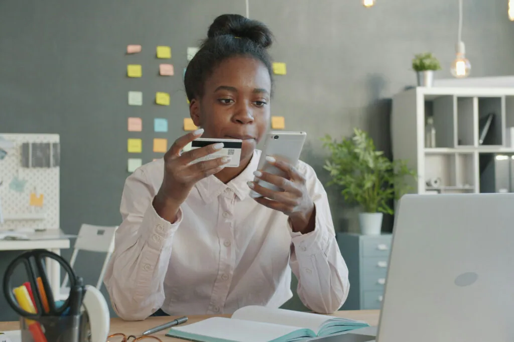 Business owner holding a credit card and phone at her desk, weighing small business financing