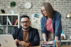 Small business owner reviewing a small business SOP with a team member at a desk.