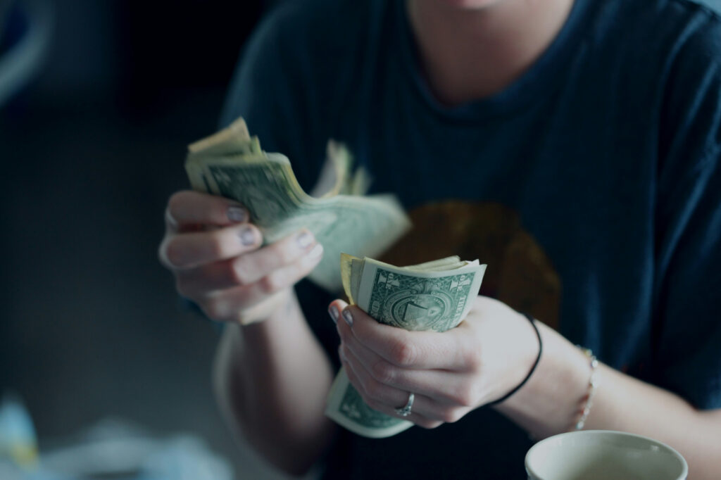 Business owner counting what's left after expenses while figuring out how to increase profit in her business.