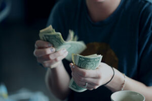 Business owner counting what's left after expenses while figuring out how to increase profit in her business.