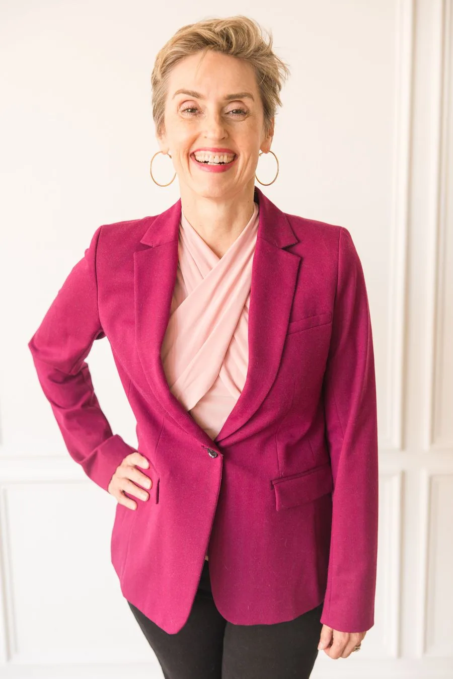 Karen Finn, PhD, business advisor and growth consultant, seated in a magenta blazer