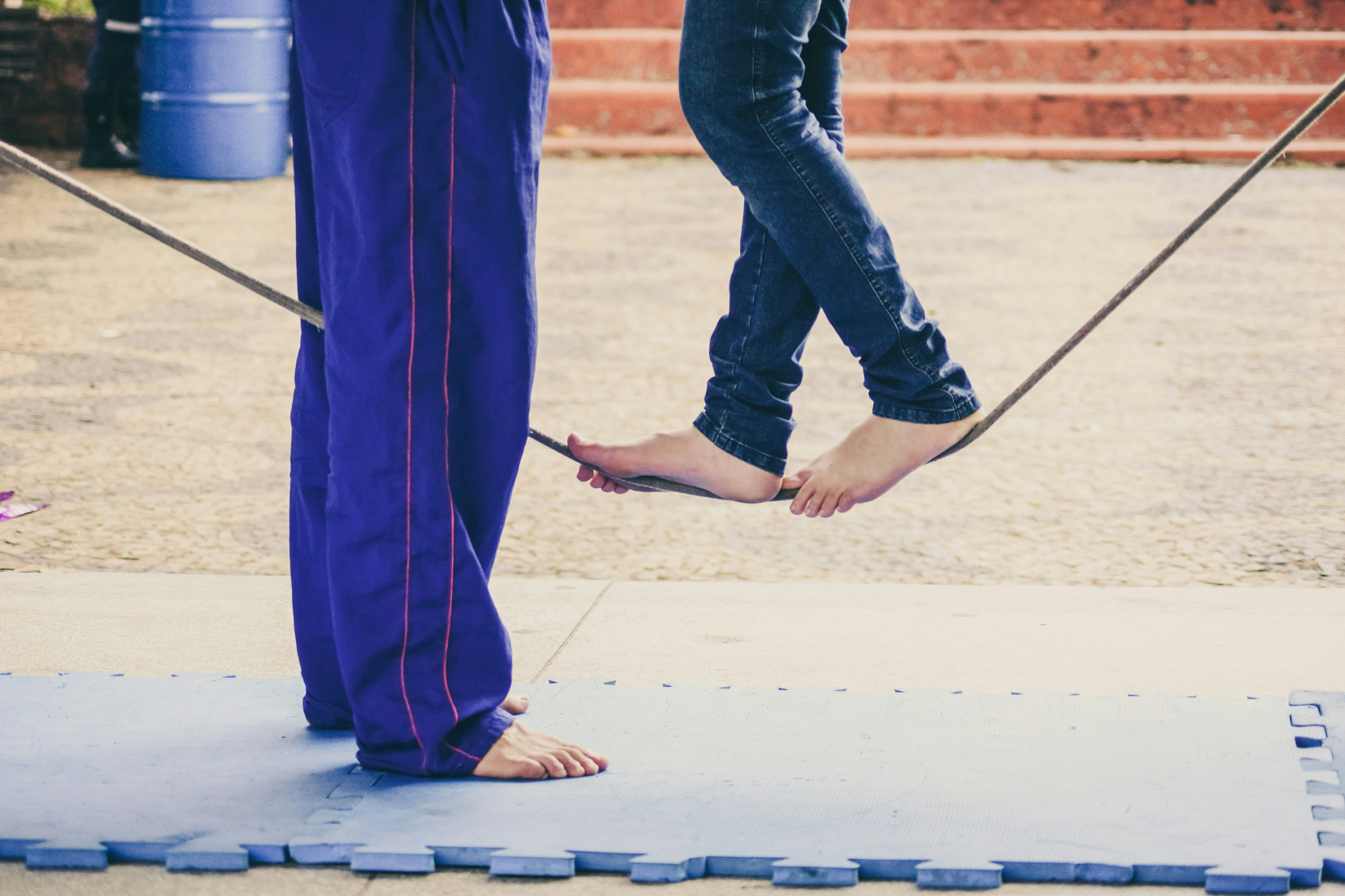 Instructor helping a student learn to walk a tightrope, a picture of support and self-awareness in leadership.