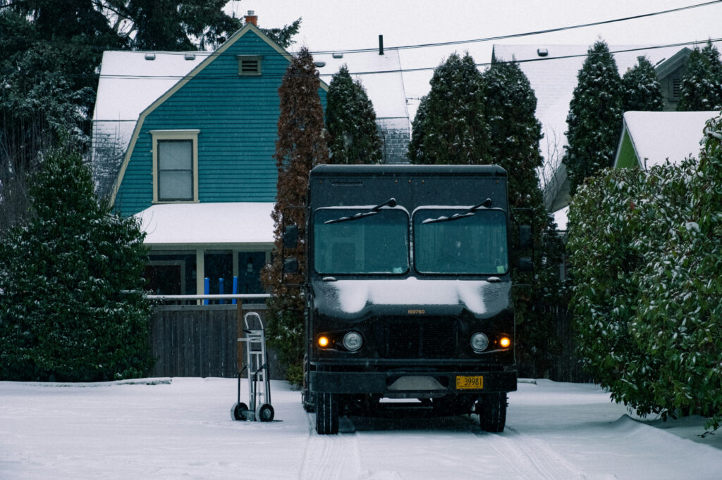 A small delivery van in a snowy driveway making a home delivery.