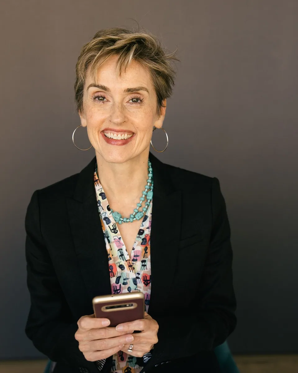 Karen Finn, PhD, smiling and holding her phone while sitting